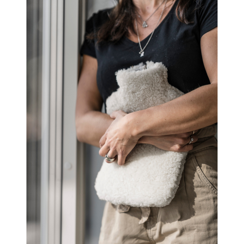 Shepherd of Sweden Sheepskin Hot Water Bottle Cover. Available in cream from our independent UK store . Seen here being held by a lady.